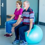 Two elderly people sitting on exercise balls representing the Wellbeing & Self-Care category.