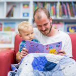 Person reading story book to a child indoors with the image representing the Families & Children category.