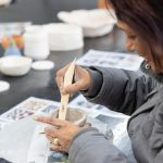 Person making a vessel from clay representing The Arts category.